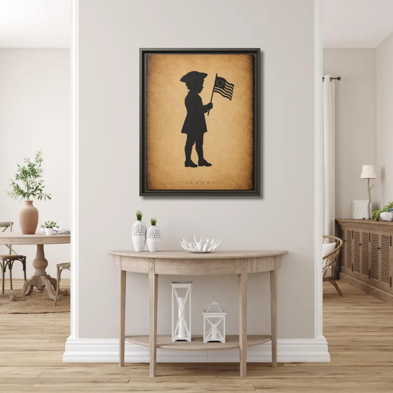 Patriot Boy with Betsy Ross Flag silhouette framed canvas hung above a demilune console table in a bright entryway with white wainscoting and oak floors