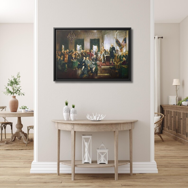 Scene at the Signing of the Constitution framed canvas hung above a demilune console table in a bright, airy entryway with light oak flooring